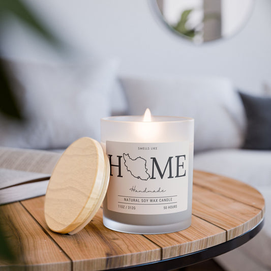Candle labeled smells like 'HOME' and Iran's map on a wooden table with a blurred background