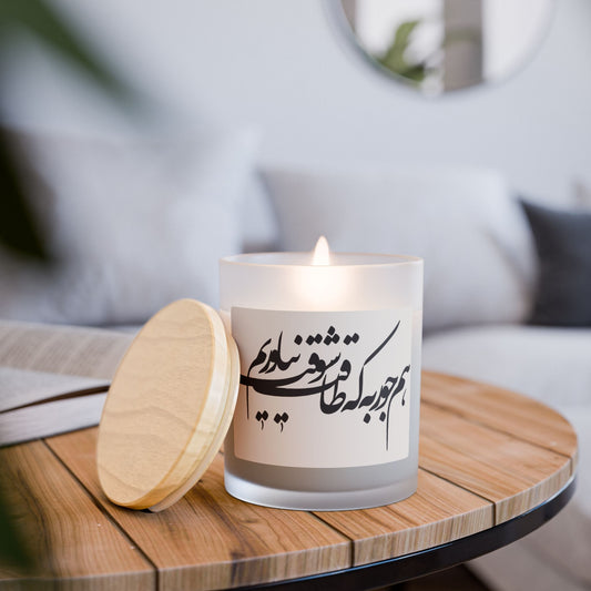Candle with Persian Farsi calligraphy text on a wooden table in a cozy indoor setting