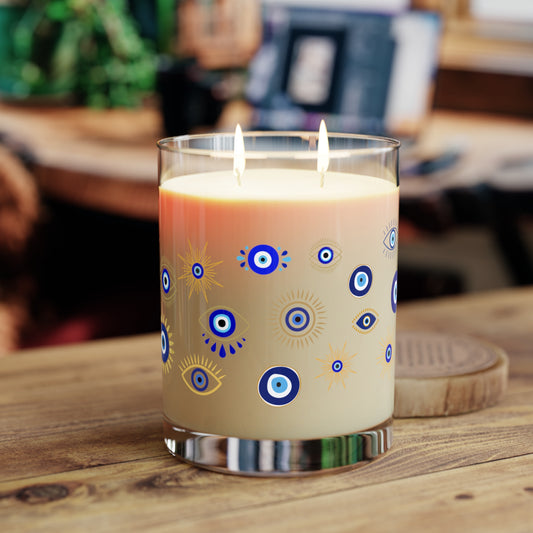 Candle with eye design in a glass holder on a wooden surface