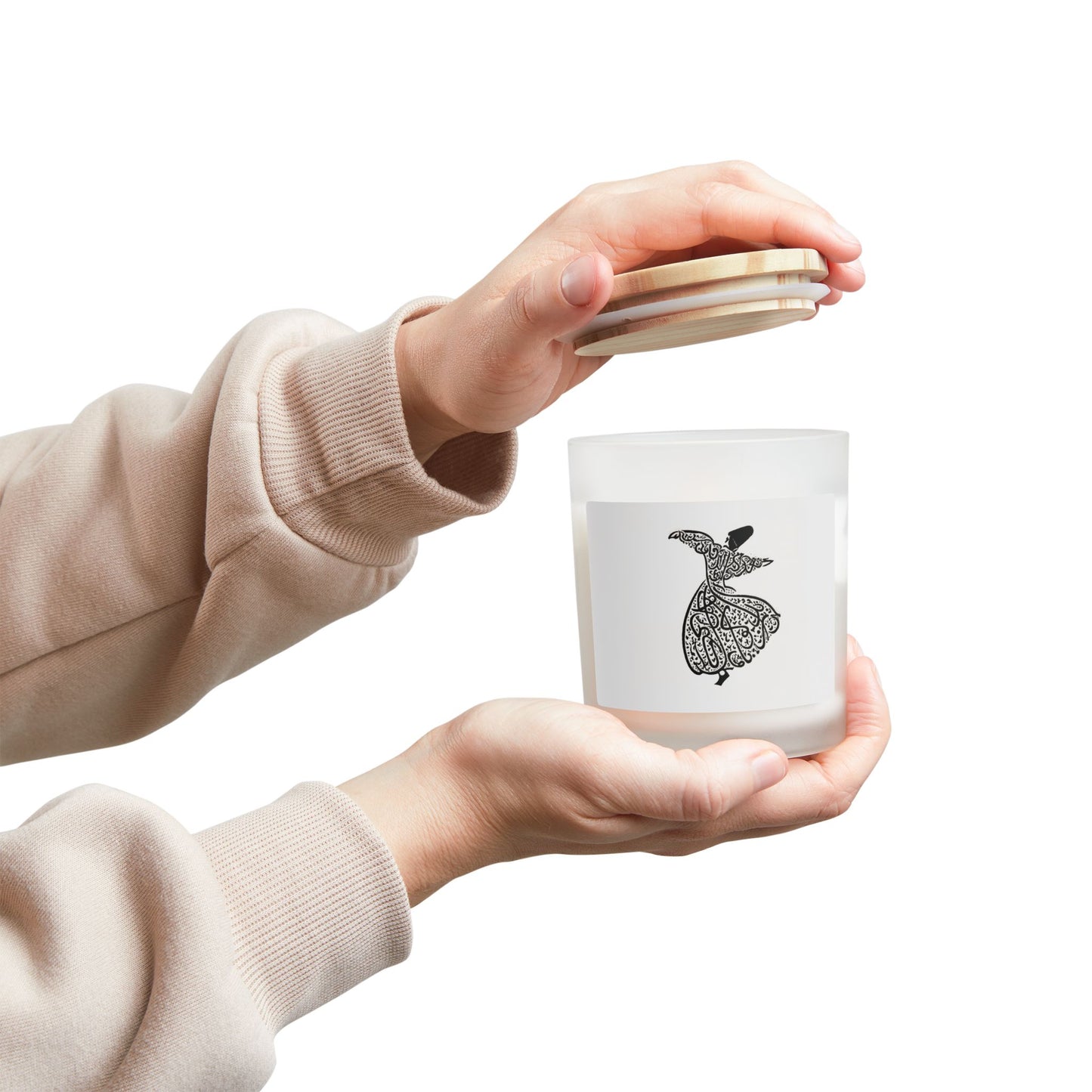 Person holding a white candle with a black design and a wooden coaster.