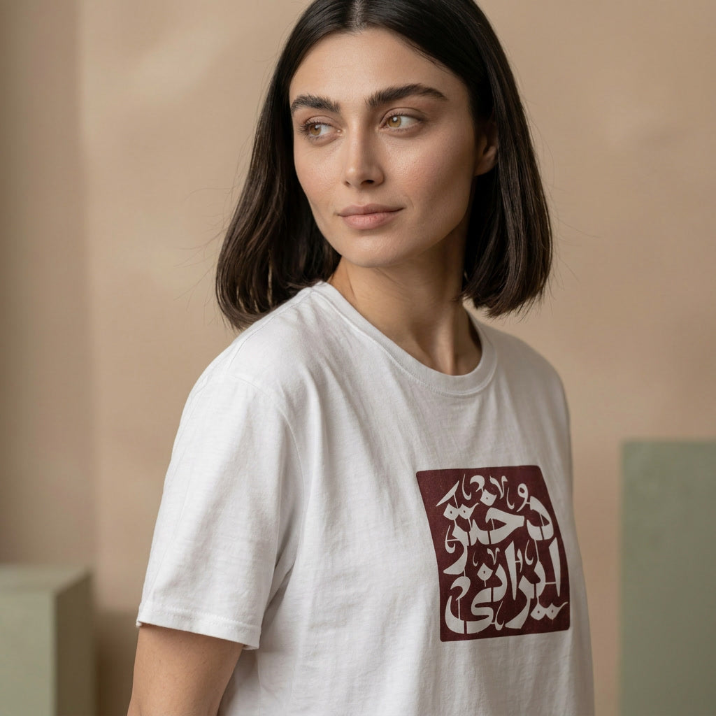 Woman wearing a white t-shirt with Farsi text design against a beige background