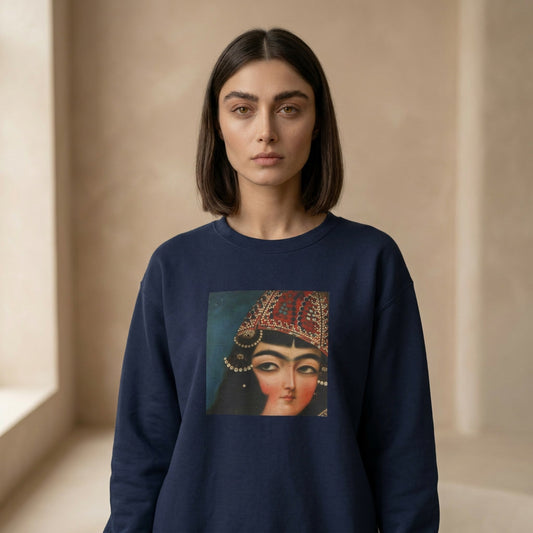 Woman wearing a navy blue sweatshirt with a graphic of a Qajar woman's face on a beige background
