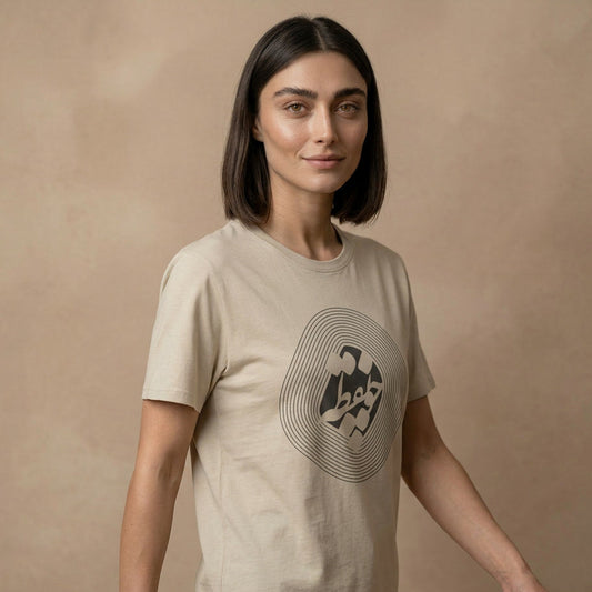 Woman wearing a beige t-shirt with a graphic design and farsi calligraphy on a beige background