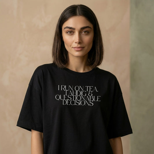 Person wearing a black t-shirt with I run on tea, tahdig & questionable decisions text on the chest. 